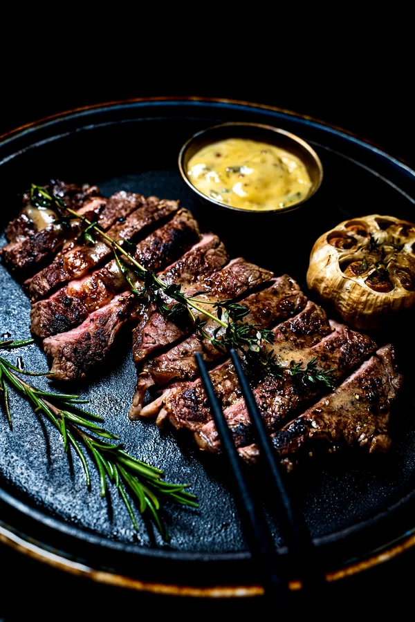 Gesneden steak met tijm, rozemarijn, geroosterde knoflook en saus